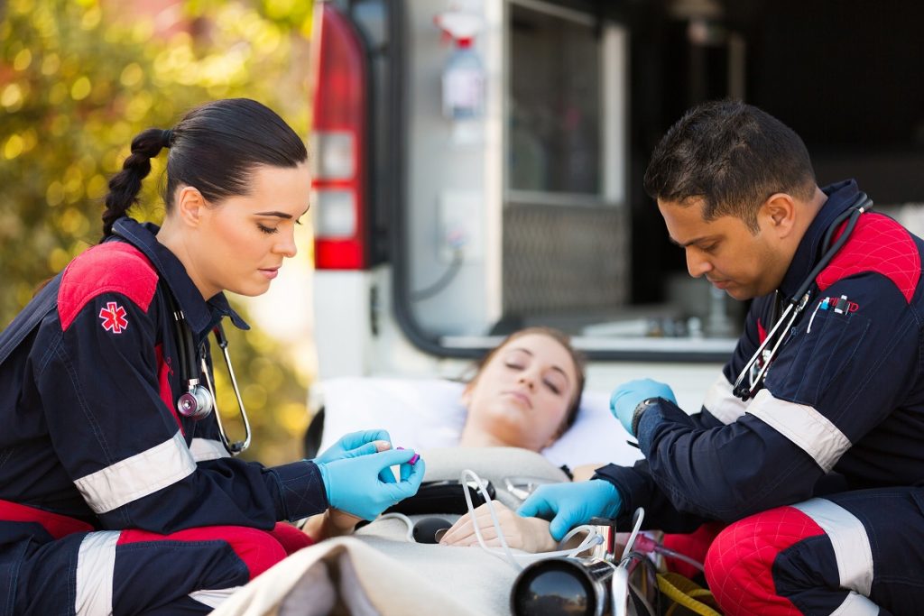 professional paramedics assisting unconscious woman